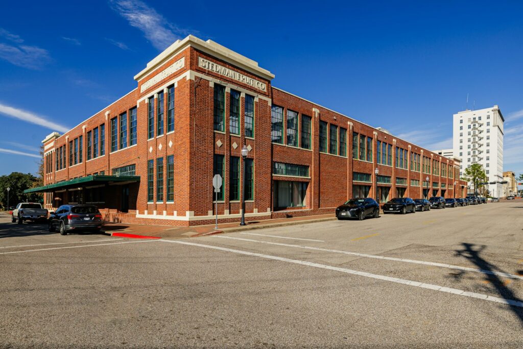 An empty parking lot in front of a large brick building